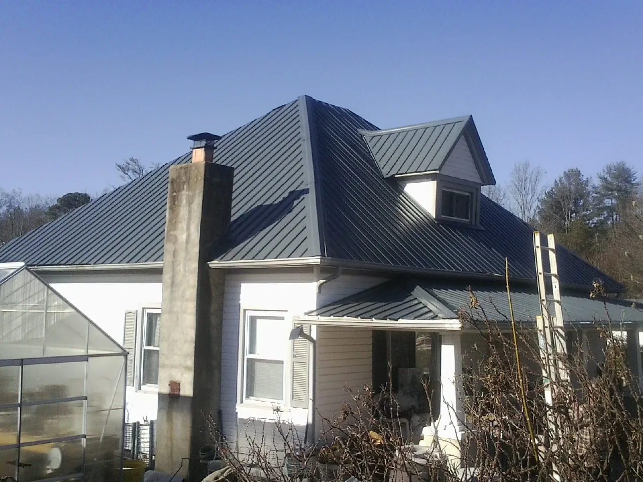 Dark blue standing seam metal roof on a white farmhouse with dormer — Slate & Tile Roof Repair by Roofing Brothers in Mc Kees Rocks