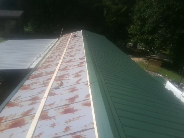 Old rusted panels beside newly installed green metal roofing — Wind Damage Roof Repair by Roofing Brothers in Mc Kees Rocks