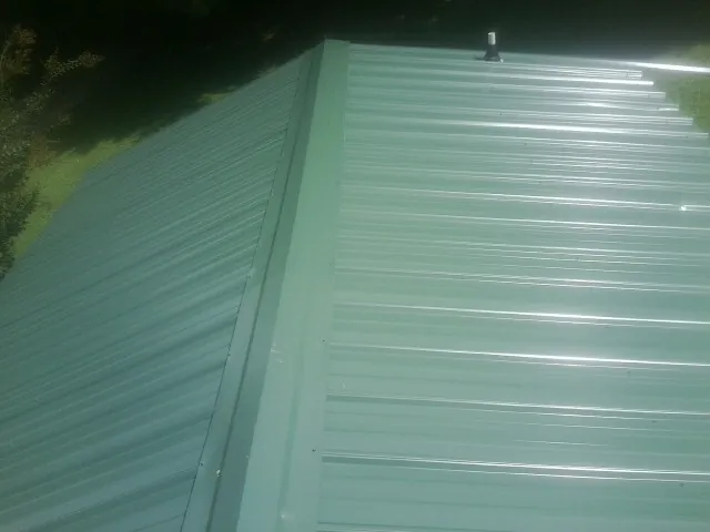 New green metal panels meeting at the ridge of a roof — Flat Roof Repair work by our crew in Mc Kees Rocks