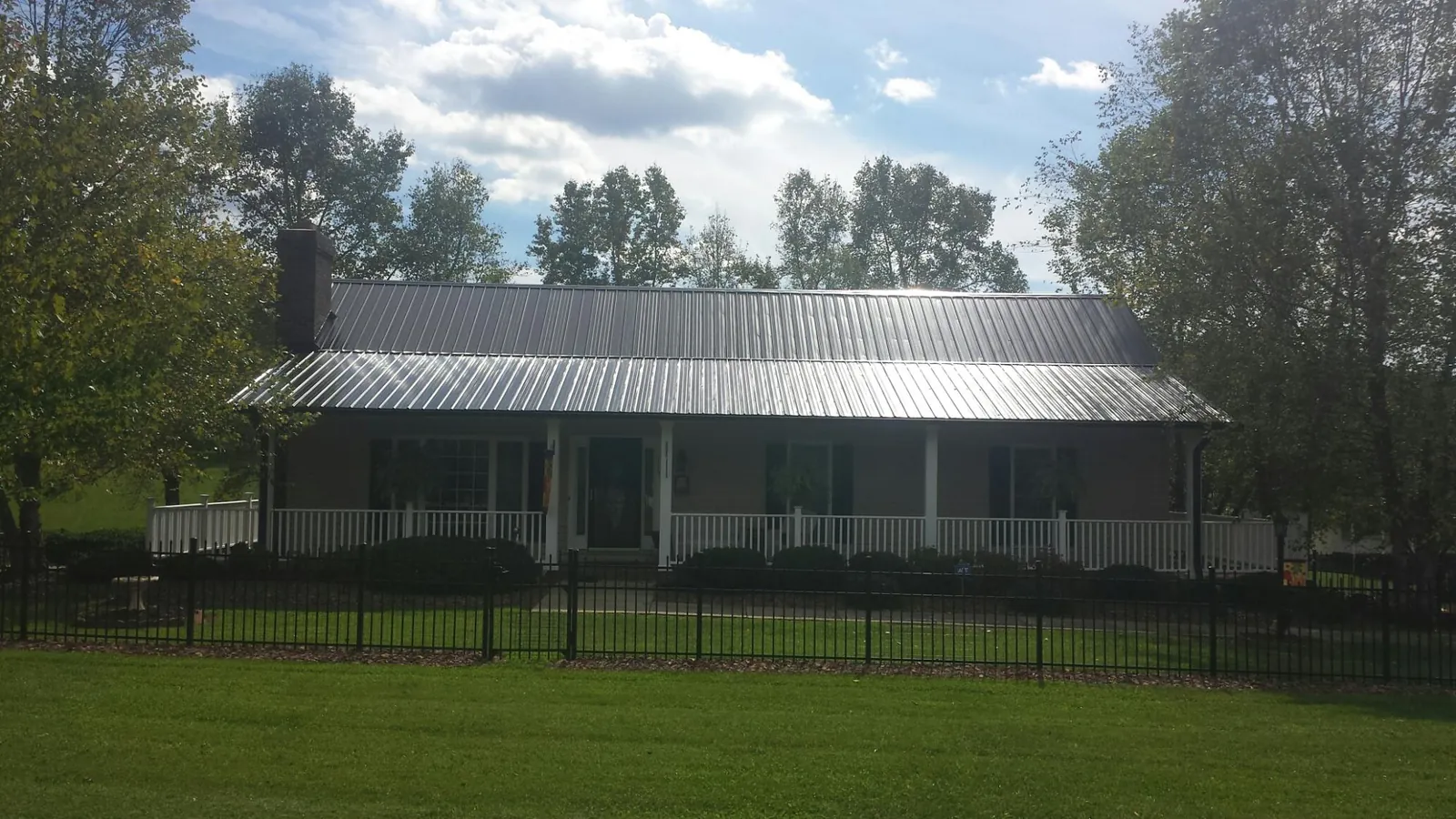 Gray metal roof on a brick ranch with a full width front porch — Gutter Guard Installation work by our crew in Mc Kees Rocks