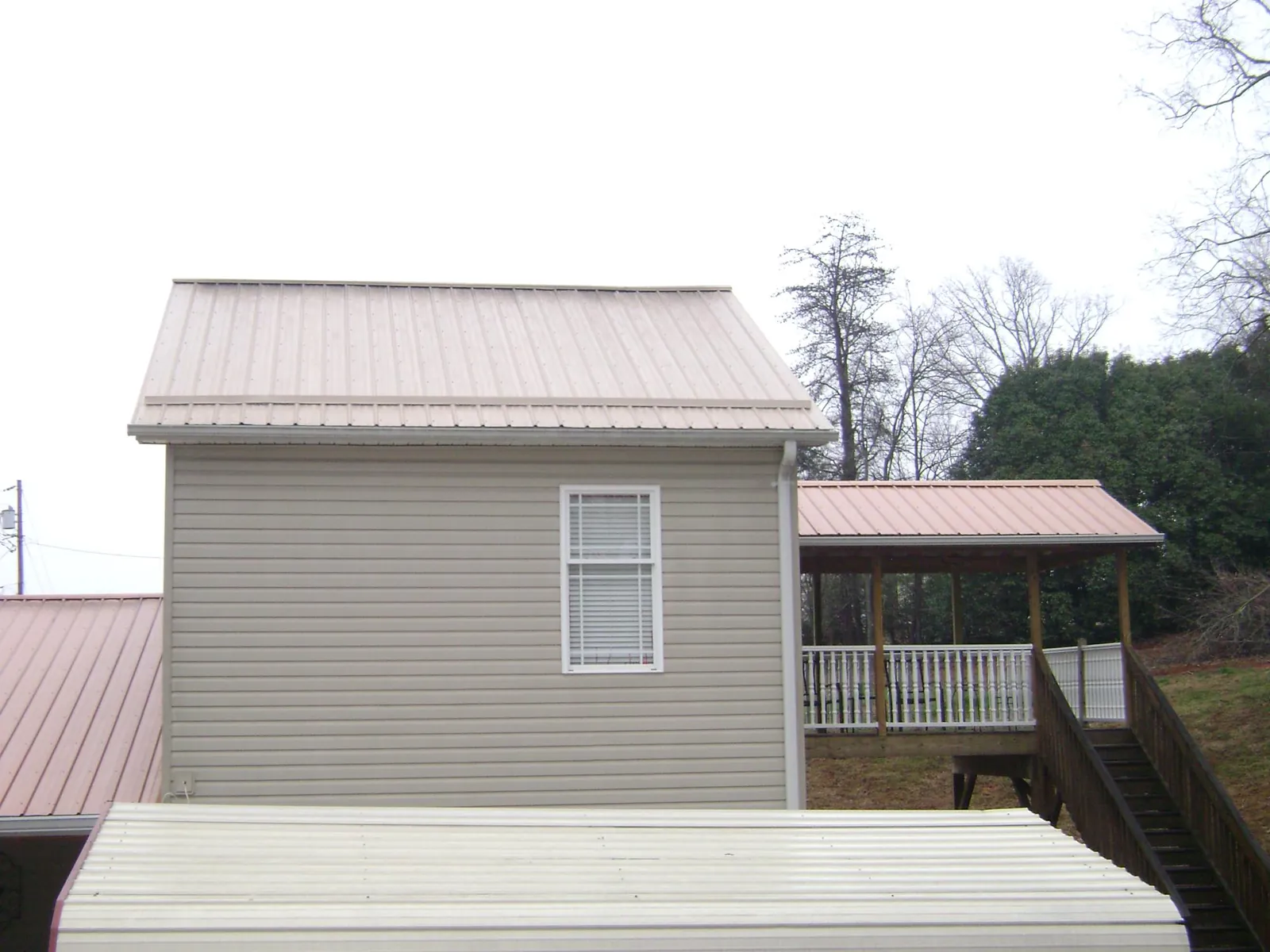 Tan metal roofs on a two story addition and attached porch, from a Roof Replacement job in Mc Kees Rocks