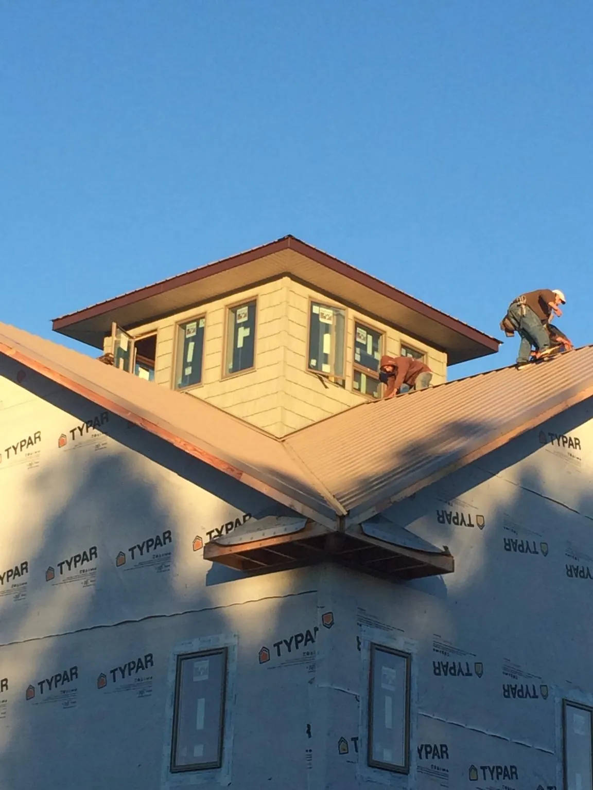 Roofers working around a rooftop cupola on a new metal roof at sunset — Roof Waterproofing in Mc Kees Rocks by Roofing Brothers